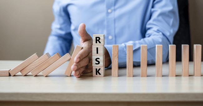 Businessman hand stopping falling wooden blocks or dominoes